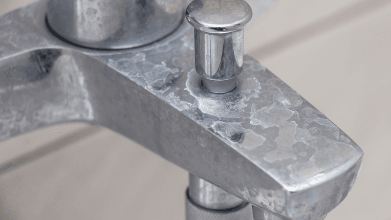 Common signs of hard water in a home: spotted glassware, soap film, and mineral crust on fixtures